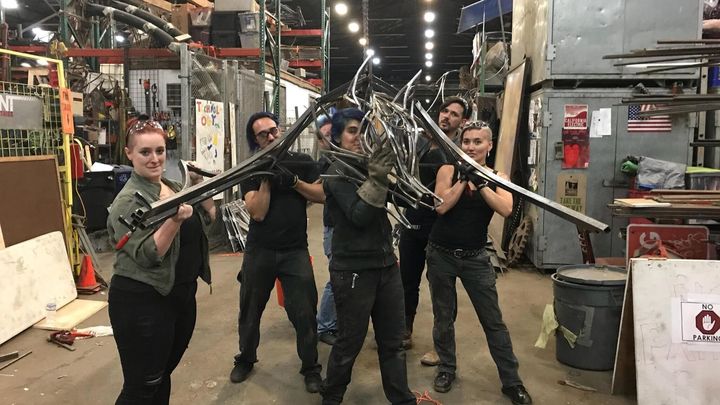 group photo of 6 artists holding up their metal sculptures