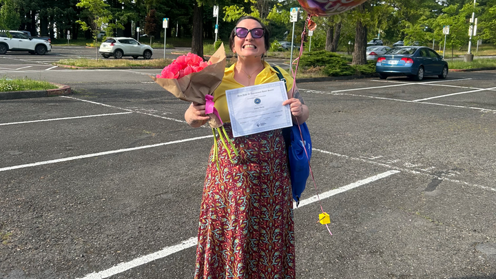 photo of student with flowers and a certificate